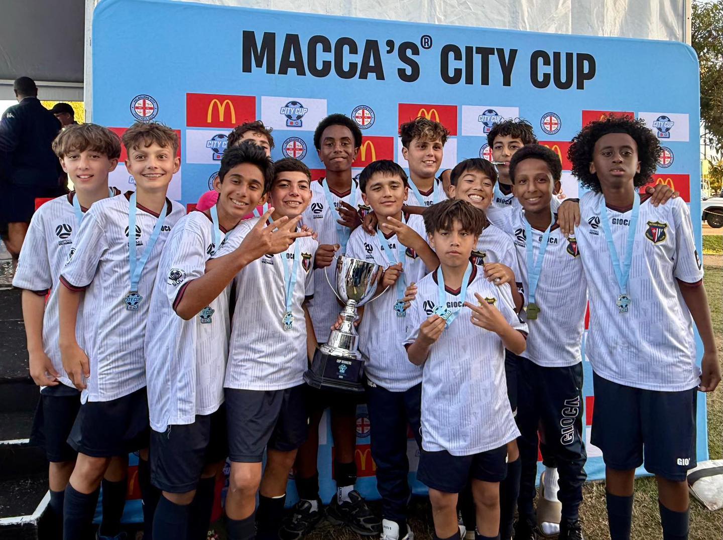 Altona North SC junior players celebrating a tournament victory with trophy